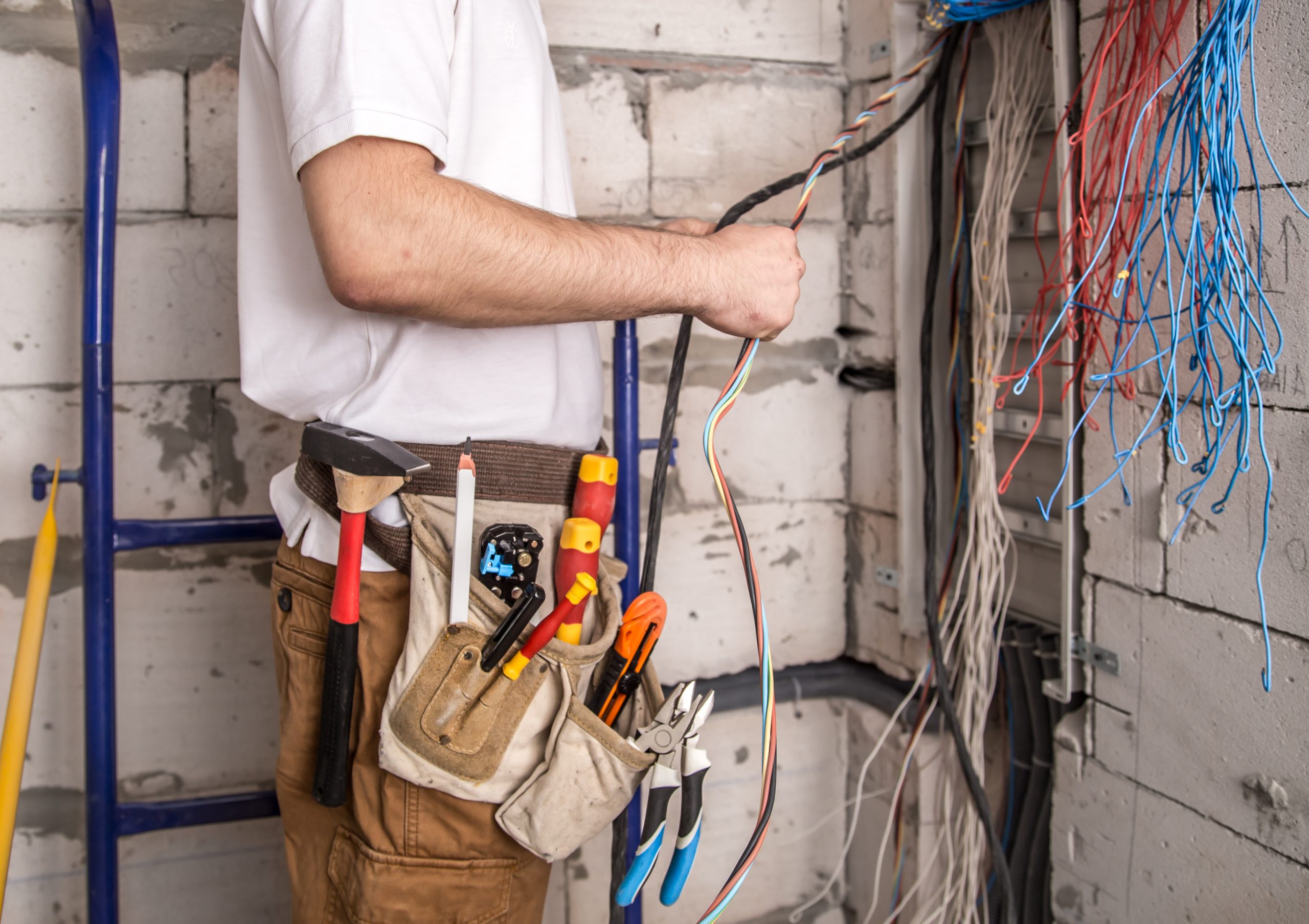 électricien réalisant une maintenance sur tableau électrique d'une maison
